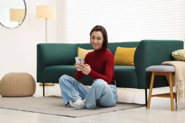 Evde modern akıllı telefon kullanan bir kadın.