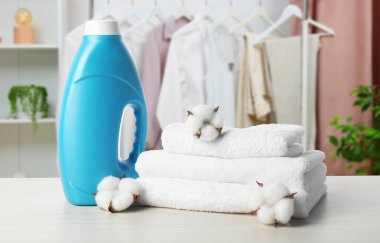 Kumaş yumuşatıcısı, havlular ve pamuk çiçekleri masanın üzerinde.