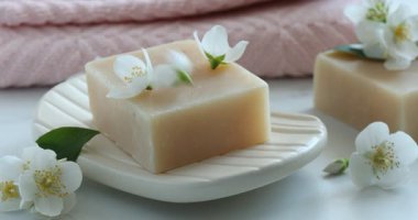 Güzel yasemin çiçekleri beyaz masadaki sabun kalıbının üzerine düşüyor.