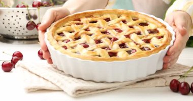 Beyaz ahşap masaya lezzetli vişneli turta koyan kadın, yakın plan.