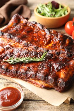 Biberiyeli, soslu ve ahşap masada salatalı domuz pirzolası.