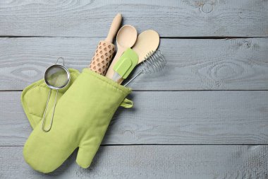 Fırın eldivenindeki farklı mutfak aletleri açık gri ahşap masa, üst manzara. Metin için boşluk