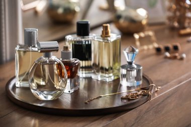 Farklı parfüm şişeleri ve aksesuarlar ahşap masada, yakın plan.