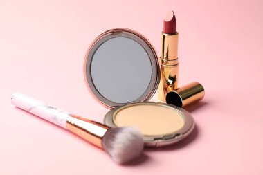 Aynalı açık yüz pudrası, pembe arka planda ruj ve fırça, yakın plan