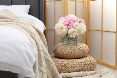 Yan masada yatağın yanında çiçekler var.