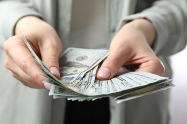 Kadın içeride dolar sayıyor, yakın çekim manzarası var.