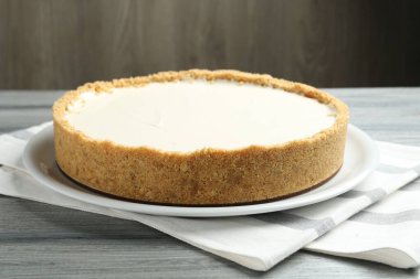 Gri ahşap masada kahverengi arka planda lezzetli bir cheesecake, yakın plan.