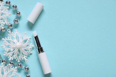 Nemlendirici dudak kremi ve açık mavi arka planda Noel dekoru, düz yatış. Metin için boşluk