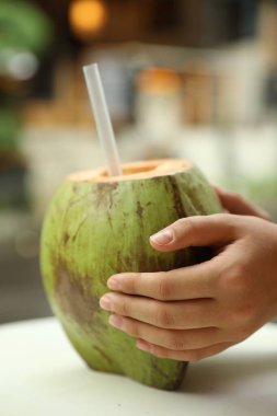 Yeşil hindistancevizli bir kadın, açık havada taze bir içecek, yakın plan.