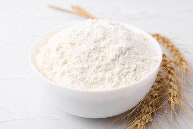 Buğday unu kasede ve çiviler beyaz masada, yakın plan.