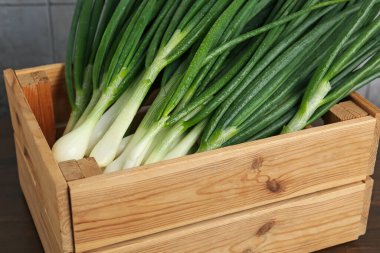 Tahta masadaki sandıkta taze taze taze soğanlar, yakın plan.