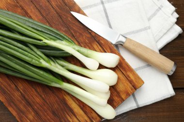 Taze taze soğanlar, tahta kesme tahtası ve bıçakla tahta masada, düz yatıyordu.