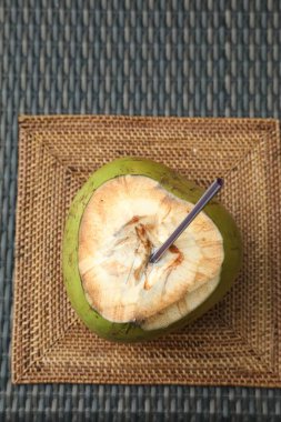 Yeşil hindistan cevizi, taze içecek ve hasır masa üzerinde saman, üst görünüm