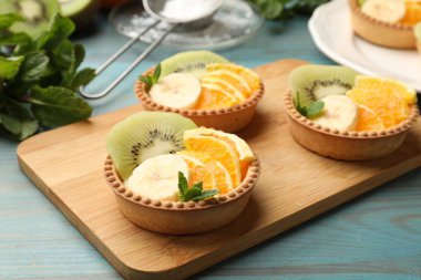 Meyveli tart ve açık mavi ahşap masada nane şekeri, yakın plan. Tatlı nefis.