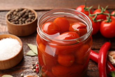 Kavanozda salamura domates ve ahşap masada malzemeler, yakın plan.