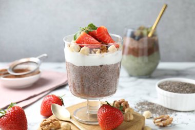 Chia tohumlu çikolatalı puding, çilek, yoğurt ve fındıklar beyaz mermer masada, yakın plan.