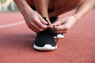 Stadyumda ayakkabı bağcığı bağlayan adam, yakın plan.