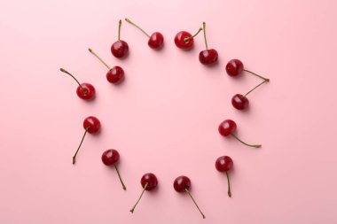 Pembe arka planda taze olgun kiraz çerçevesi, düz. Metin için boşluk