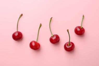 Pembe arka planda taze kirazlar, düz uzanmış.