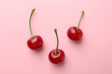 Pembe arka planda taze kirazlar, düz uzanmış.