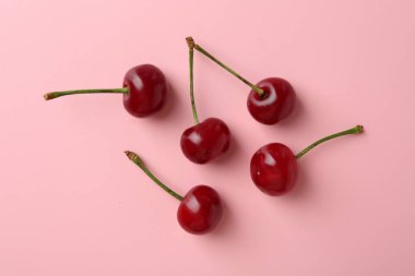 Pembe arka planda taze kirazlar, düz uzanmış.