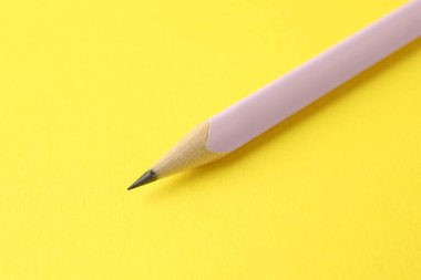 Sarı arkaplanda bir grafit kalem, yakın plan.