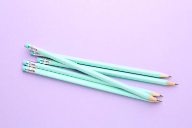 Menekşe arkaplanda silgileri olan birçok grafit kalem, düz konum