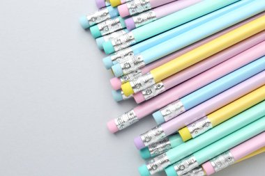 Açık gri arkaplanda silgisi olan bir sürü grafit kalem, düz bir zemin. Metin için boşluk