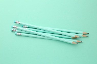 Turkuaz arka planda silgileri olan birçok grafit kalem, düz konum