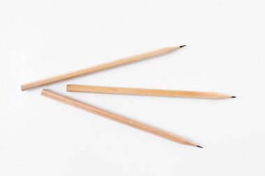 Beyaz zemin üzerinde üç grafit kalem, düz yatıyordu.