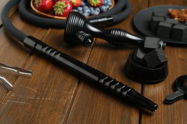 Geleneksel nargile parçaları, kömür küpleri ve ahşap masadaki böğürtlenler.