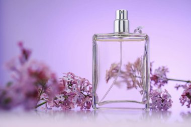 Bir şişe parfüm ve ayna yüzeyinde eflatun rengine karşı leylak çiçekleri, seçici odak