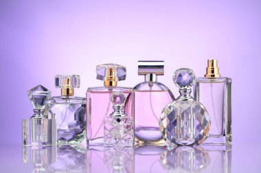 Ayna yüzeyinde mor arkaplana karşı parfüm şişeleri ve leylak çiçekleri