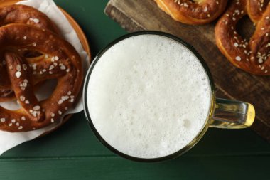 Lezzetli krakerler ve yeşil ahşap masada bir bardak bira.