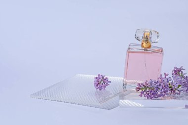 Açık gri arka planda parfüm şişesi ve leylak çiçeklerinin şık sunumu, yakın plan. Metin için boşluk