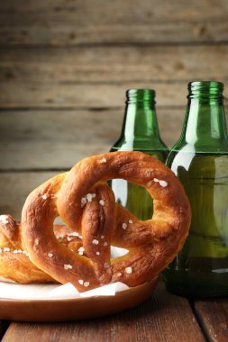 Lezzetli krakerler ve bira şişeleri ahşap masada, yakın plan.