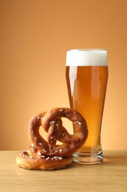 Lezzetli krakerler ve ahşap masada bir bardak bira bej renkli arka plan, yakın plan.