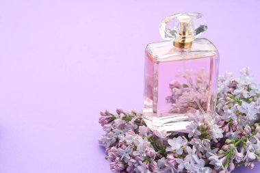 Parfüm şişesi ve mor arka planda leylak çiçekleri, yakın plan. Metin için boşluk