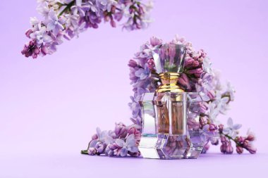 Parfüm şişesi ve mor arkaplanda leylak çiçekleri, yakın plan.