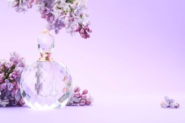 Parfüm şişesi ve mor arkaplanda leylak çiçekleri, yakın plan. Metin için boşluk