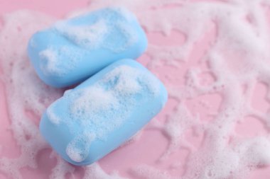 Pembe arka planda köpüklü sabun çubukları. Metin için boşluk