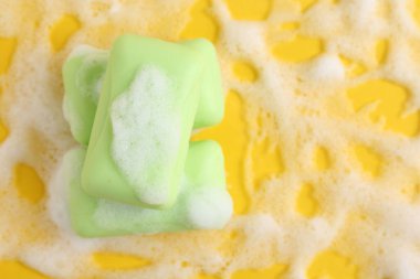 Sarı arka planda köpüklü sabun çubukları, üst manzara. Metin için boşluk