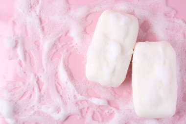 Pembe arka planda köpüklü sabun kalıpları, düz yatış. Metin için boşluk