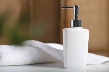 Şişede sıvı sabun ve beyaz masa içinde havlu.