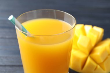 Bardakta lezzetli mango suyu ve masada taze meyve, yakın plan.