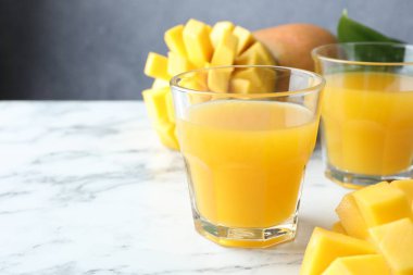 Bardakta lezzetli mango suyu ve beyaz mermer masada taze meyve, yakın plan. Metin için boşluk