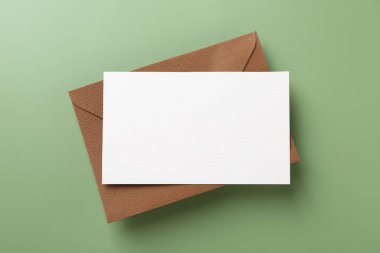 Açık yeşil arkaplanda boş davetiye ve zarf, üst görünüm