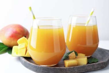 Bardakta lezzetli mango suyu ve beyaz masada taze meyve, yakın plan.