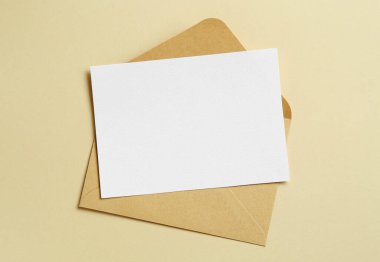 Bej arka planda boş davetiye ve zarf, üst manzara. Tasarım için boşluk