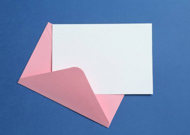 Mavi arka planda boş davetiye ve zarf, üst manzara. Tasarım için boşluk